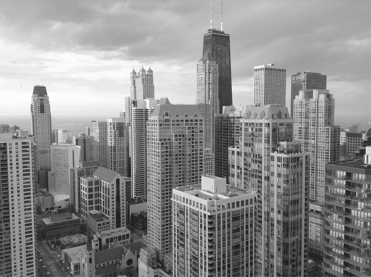 Black-and-white aerial view of a city skyline of high-rise towers.